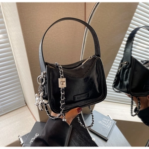 Détail du sac bandoulière en cuir noir avec chaîne argentée et breloque chien ballon
