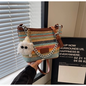 Detail of colorful woven bucket bag with metal chain handle and plush monster charm