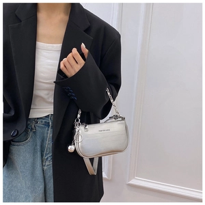 Sac sous le bras argenté avec bandoulière chaîne et breloque sphère sur blazer noir