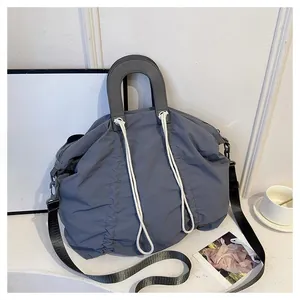 Macro shot of grey pleated nylon tote bag with white rope detail and leather handle