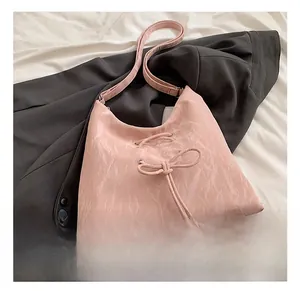 Detailed macro shot of the pink pleated shoulder bag with decorative bow and shiny texture