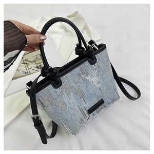 Detailed view of light blue denim fabric with silver sequins and black leather straps
