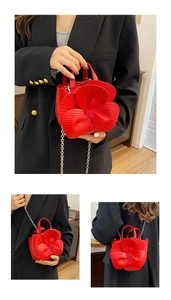 Detail view of red petal bucket bag showing crossbody chain strap and handbag handles