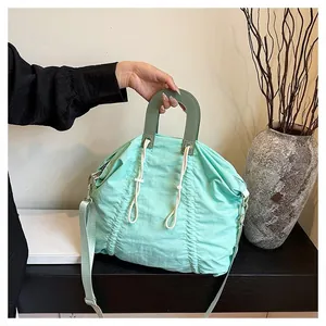 Detail of mint green drawstring bag with pleated texture and olive green handle handle