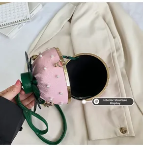 Close-up of pink strawberry-shaped bucket bag with pearl accents and green leaf handle