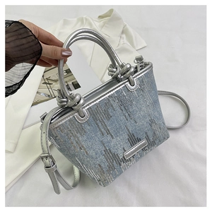 Detail of blue denim handbag with silver sequins, metallic handle and knot design