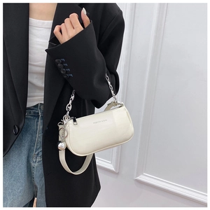 Détail d'un sac baguette blanc brillant avec chaîne argentée et breloque boule en métal