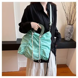 Detail of mint green pleated drawstring handbag with contrasting green handles and strap