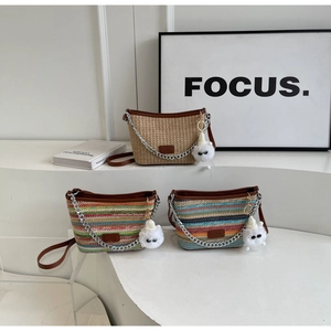 Detail of woven straw bucket bags with leather trim and decorative plush charms