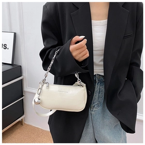 Détail du sac à bandoulière en cuir blanc avec chaîne argentée et breloque en métal