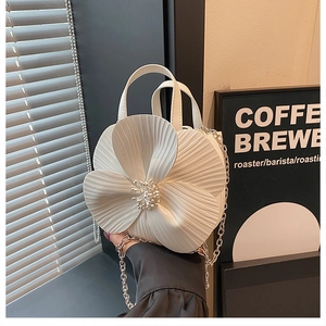 Detail of white 3D camellia bucket bag showing petal pleats and pearl center embellishments