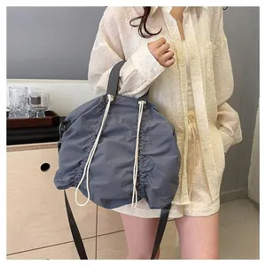 Detail of dark grey pleated nylon tote bag with white drawstring and soft texture