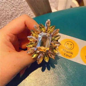 Detailed view of sunflower shaped gold crystal phone grip held against a green surface