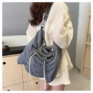 Detailed view of grey pleated canvas tote bag featuring curved hard handles and shoulder strap