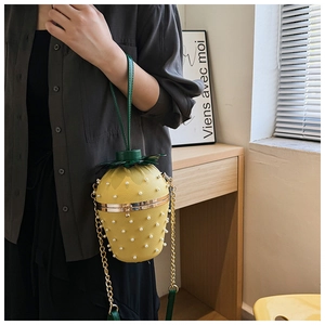 Close-up of strawberry-shaped handbag featuring yellow textured finish and pearl accents