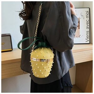 Detail of yellow pineapple bucket bag with pearl accents and metal chain strap