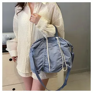 Close-up of light blue pleated nylon tote bag with drawstring texture and adjustable strap