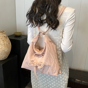 Detailed view of pink bow-knot backpack with pleated texture and stylish ribbons