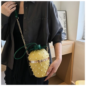 Close-up of strawberry-shaped pineapple bucket bag with pearls and chain strap on model