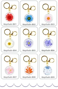 Grid view of nine resin keychains featuring real dried flowers in gold metal rings