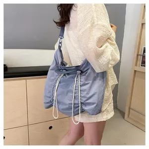 Detail of light blue nylon pleated shoulder bag with adjustable drawstring and wide strap
