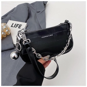 Détail du sac croissant noir texturé avec chaîne argentée et pendentif boule