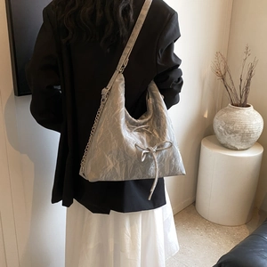 Detail of silver metallic hobo bag with bow drawstring and mixed chain leather strap