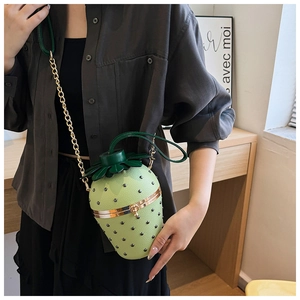 Detail of light green strawberry-shaped bag with gold chain strap and rivet textures