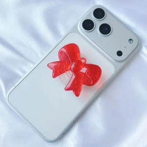 Detail of red translucent 3D bow phone grip on light smartphone over white silk background