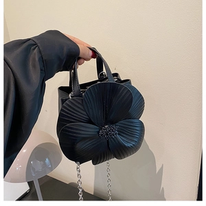Detailed view of the 3D flower petal design and beaded center on a black bucket bag