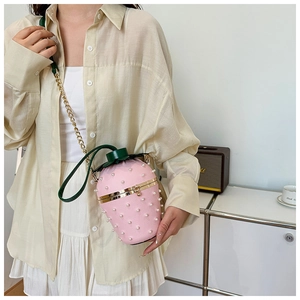 Detail view of a strawberry-shaped crossbody bag with pearl embellishments and chain strap