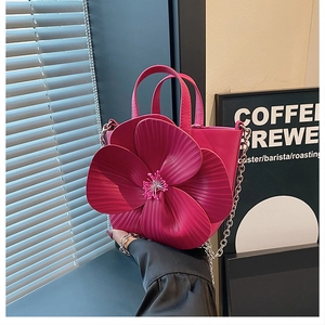 Detail of rose red bucket bag with 3D flower decoration and silver chain strap