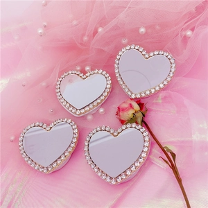 Détail de supports de téléphone miroir en cœur avec strass sur fond en tulle rose