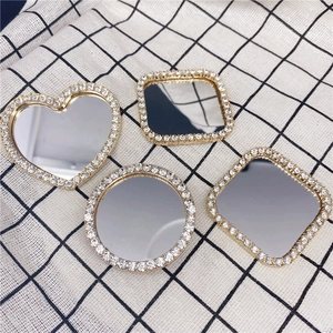 Macro shot of gold rhinestone-studded mini mirrors in heart, round, and square shapes