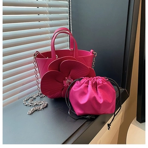 Detail view of rose pink bucket bag featuring a large 3D flower and satin drawstring pouch
