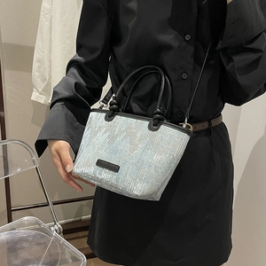 Chic blue sequin tote bag with black leather handles and shoulder strap shown on model