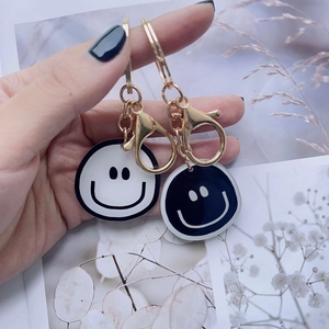 Close-up of minimalist black and white smiley face keychains with gold metal lobster clasps