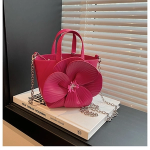 Detailed view of rose red bucket bag with 3D floral accent and silver chain strap