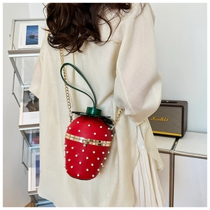 Detail of strawberry shaped chain bag with red leather and pearl beads on a model