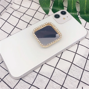 Detail of square diamond-encrusted phone mirror grip mounted on white smartphone