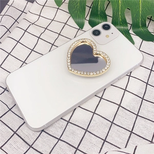 Rhinestone heart-shaped phone grip with makeup mirror on a white smartphone