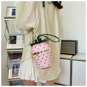 Detail of pink strawberry crossbody bag with green leaf top and gold chain strap