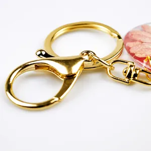 Close-up of gold lobster clasp keychain with pink real dried flower resin pendant