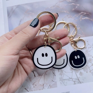 Golden plated keychain featuring black and white cartoon smiley face charms