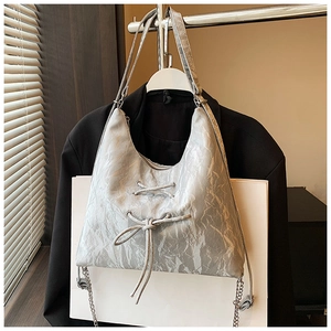 Detail of silver-grey bow shoulder bag showing crinkled metallic fabric and lace-up design