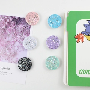 Glittery round retractable phone grip collection in six pastel colors on white surface