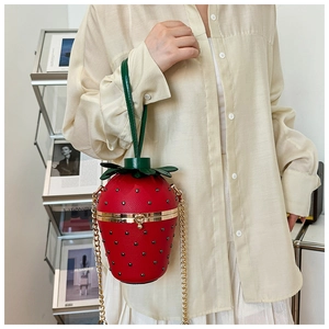 Detail of red strawberry leather bag with black rivets and gold heart-shaped lock