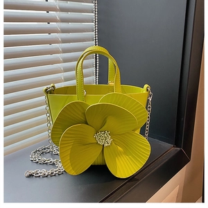 Detailed close-up of 3D camellia flower texture on bright green bucket bag with silver chain