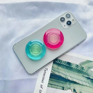 Detail showing two gradient air cushion phone grips in pink and blue on a smartphone