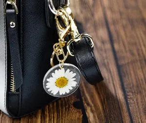 Detailed macro view of white daisy flower resin keychain on a black textured bag